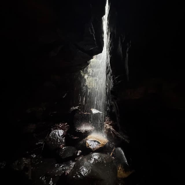 Intervals album cover: sunlight and falling water in a dark rock opening